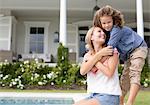 Mother and daughter hugging by swimming pool