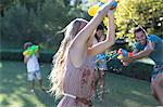 Family playing with water guns in backyard