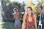 Friends playing with water guns in backyard