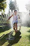 Boy playing in sprinkler in backyard