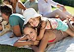 Mother and daughter relaxing in grass with family