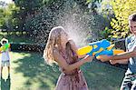 Couple playing with water guns in backyard