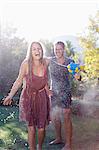 Couple playing with water guns in backyard