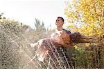 Couple playing in sprinkler in backyard