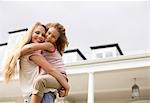 Mother and daughter hugging outside house