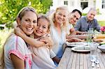 Mother and daughter hugging at table outdoors