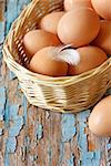Fresh farm organic eggs with feather in a basket on an old wooden board.