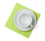 Empty white cup on green placemat. Above view. Isolated on white background