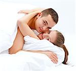 Happy young couple hugging in bed, looking to us