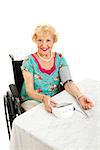 Beautiful senior woman in wheelchair taking her blood pressure with a home machine.  White background.
