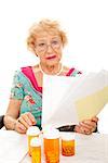 Disabled senior lady in wheelchair holding a pile of medical bills.  White background.