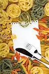 Note paper on various Italian pasta background and silverware