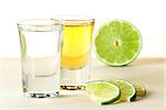 Blanc and Gold Tequila with lime slices on wood table isolated on white background