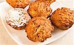 Fresh baked pumpkin muffins on a plate with sugar icing over one of them.
