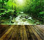 Wooden platform and tropical mountain stream with sunbeam in a morning.