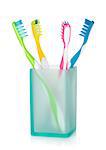 Four multicolored toothbrushes in glass. Isolated on white background