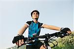 young woman training on mountain bike and cycling in park. Copy space, low angle view