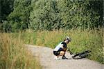 young woman training on mountain bike and repairing flat tyre on track in countryside