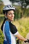 portrait of young woman training on mountain bike and smiling at camera and looking over the shoulders