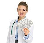 Smiling doctor woman showing fan of dollars