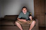 man watching tv laughing with beer