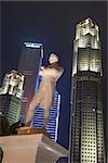 Tourism landmark symbol of Singapore, Sir Stamford Raffles statue with dramatic lighting at night with skyscrapers on background