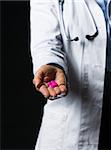 Closeup on pills in hand of doctor woman isolated on black