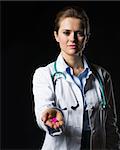 Doctor woman showing pills isolated on black