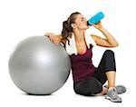 Fitness young woman with fitness ball drinking water