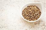 small ceramic bowl of  dry hemp seeds against a ceramic tile background with a copy space