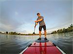 mature male paddler enjoying workout on stand up paddleboard (SUP), calm lake in Colorado, summer