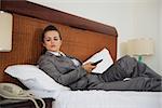 Concerned business woman laying on bed in hotel room and waiting phone call