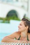 Portrait of happy young woman relaxing in pool and looking on copy space