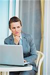 Thoughtful business woman working with laptop on terrace