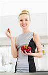Young housewife eating strawberry in modern kitchen