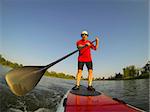 mature male paddler enjoying workout on stand up paddleboard (SUP), calm lake in Colorado, summer, distorted wide angle view