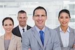 Smiling coworkers posing crossing arms in bright office