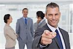 Cheerful businessman in bright office pointing at camera