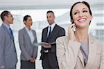 Cheerful businesswoman in bright office calling while colleagues talking together