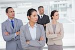 Stern work team crossing arms and looking away in bright office