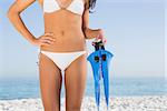 Perfect female body in white bikini holding fins on the beach