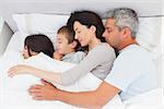 Smiling family sleeping together in bed at home
