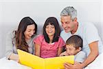 Family looking together at their photograph album in bed at home