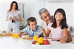 Smiling family eating breakfast in kitchen together at home