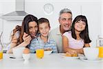 Cheerful family eating breakfast in kitchen together at home