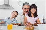Siblings eating breakfast in kitchen together with dad at home