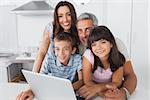 Happy family sitting in kitchen using their laptop at home
