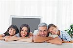 Cute family in sitting room smiling at camera at home