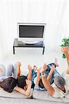 Family sitting on sofa cheering in front of television at home