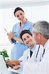 Happy nurse listening to doctors talking about something on their laptop in medical office